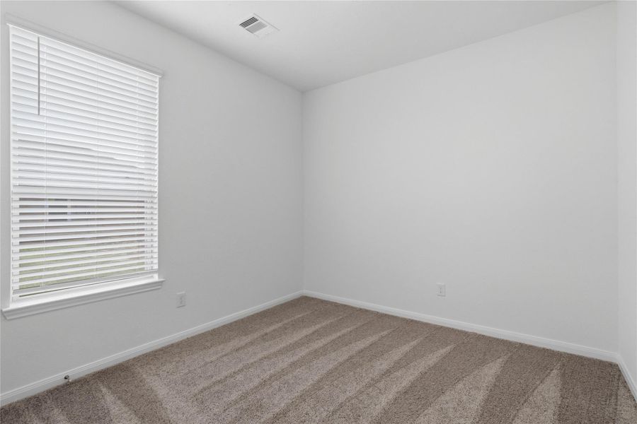 Light-filled secondary bedroom complete with cozy carpet flooring, ample closet space, and a large window wth fitted blinds.