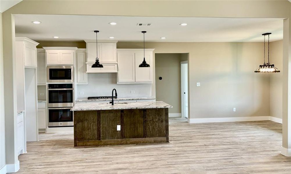 Kitchen featuring appliances with stainless steel finishes, light wood finished floors, recessed lighting, and white cabinetry Kitchen featuring appliances with stainless steel finishes, light wood finished floors, recessed lighting, and white cabinetry