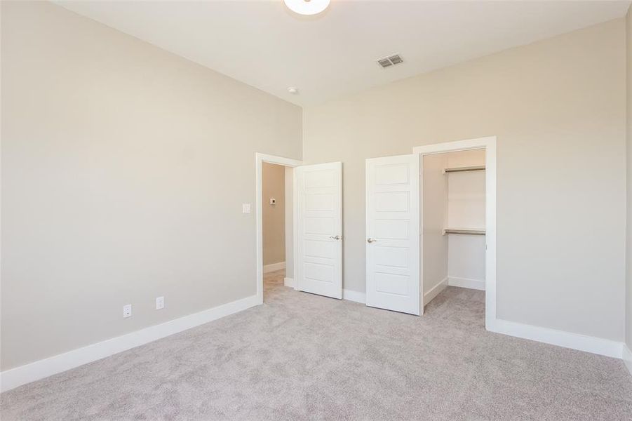 Unfurnished bedroom featuring a spacious closet, light carpet, and a closet