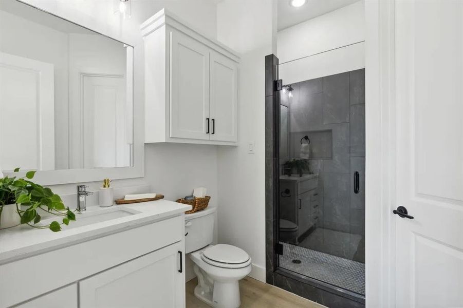 Full bath with vanity, a shower stall, and light wood-type flooring