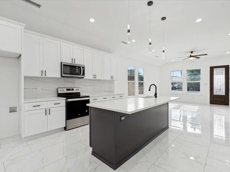 Kitchen with a kitchen island with sink, tasteful backsplash, stainless steel appliances, white cabinets, and light tile patterned flooring