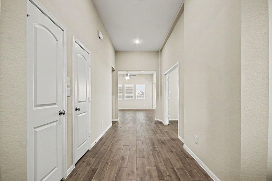 Inviting entryway with high ceilings and wood-look flooring leads to a bright living area, offering a modern and spacious feel. Two closets off the entryway for extrastorage.