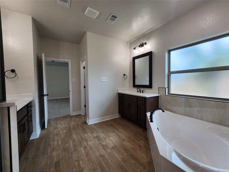 Indulge in a tranquil bathing experience with a freestanding tub and wood-look tile flooring in this primary bath. Indulge in a tranquil bathing experience with a freestanding tub and wood-look tile flooring in this primary bath.