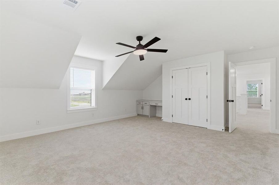 Spacious room featuring light-colored carpeting, a window with blinds, and white built-in cabinetry with a desk area Spacious room featuring light-colored carpeting, a window with blinds, and white built-in cabinetry with a desk area