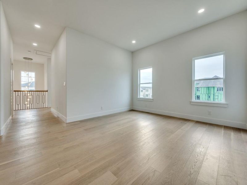 Spare room featuring an inviting chandelier, light hardwood / wood-style floors, and plenty of natural light