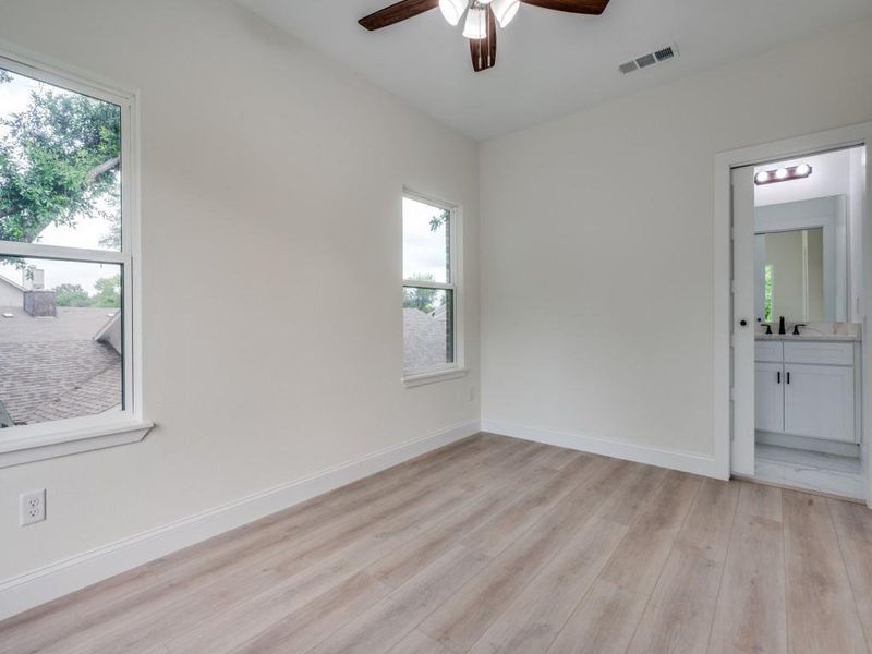 Spare room featuring ceiling fan, healthy amount of natural light, light wood-style floors, and baseboards