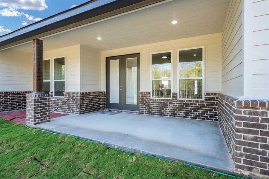 Generous covered patio with sophisticated farmhouse details and dual access through French doors. Exceptional outdoor living area ideal for year-round enjoyment of the tranquil country setting.