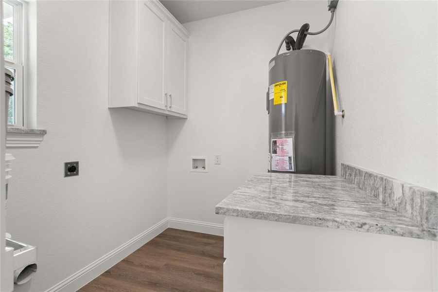 Laundry area featuring white shaker-style cabinetry, a gray patterned countertop, wood-finish flooring, and white baseboards