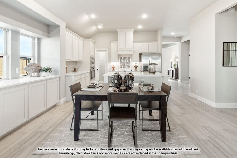 Open dining area with dark wood table flowing into white kitchen with island and light wood floors