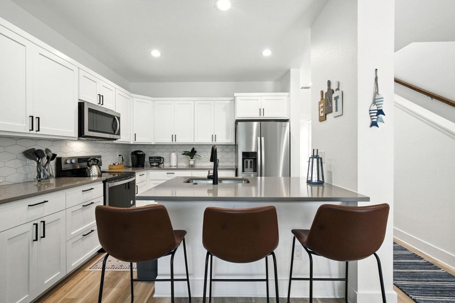 Kitchen with a breakfast bar, stainless steel appliances appliances, light vinyl plank flooring, white self-close cabinets, and recessed lighting Kitchen with a breakfast bar, stainless steel appliances appliances, light vinyl plank flooring, white self-close cabinets, and recessed lighting