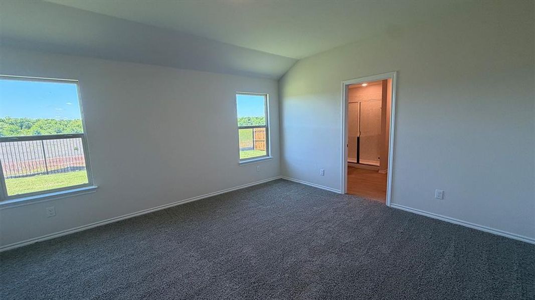 Spacious room with vaulted ceilings and gray carpet flooring