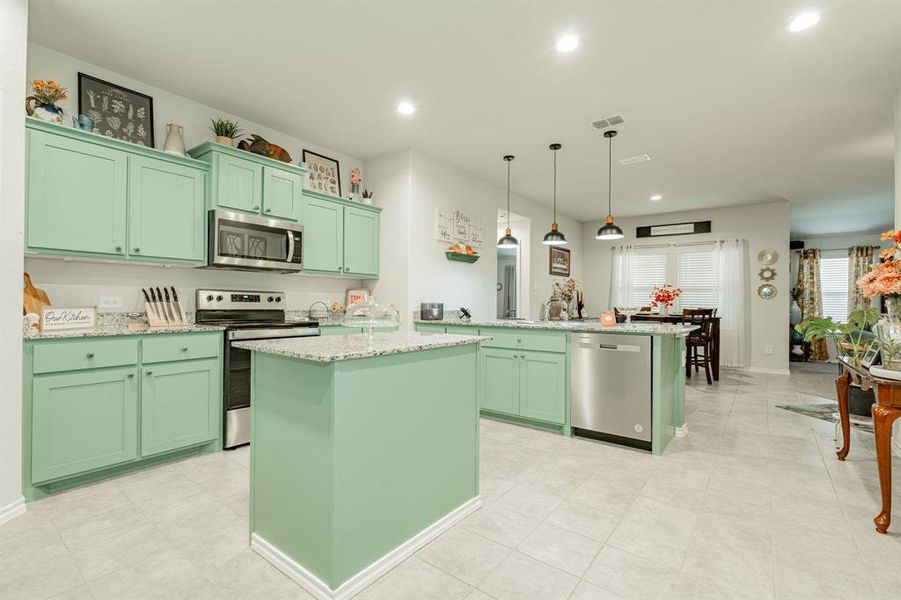 Kitchen with green cabinets, recessed lighting, appliances with stainless steel finishes, and a kitchen island