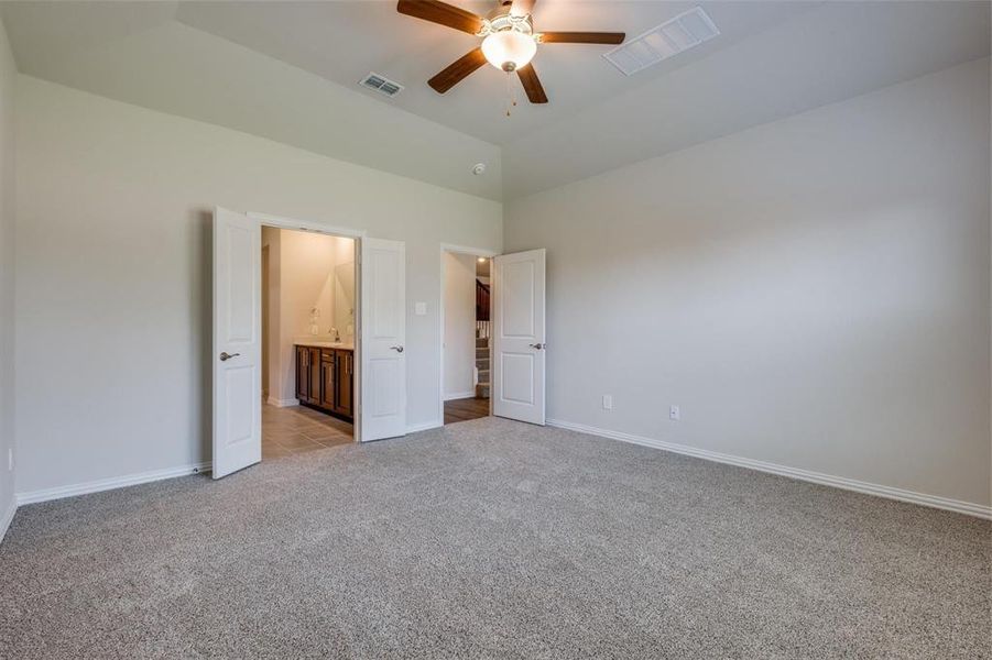 Unfurnished bedroom featuring light carpet, ensuite bathroom, high vaulted ceiling, and ceiling fan