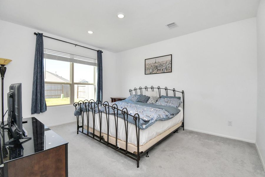 A generously sized primary bedroom that still has plenty of "air space" and "floor space" even with large furniture inside.