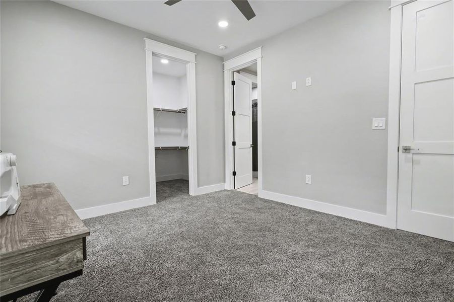 Spacious room featuring plush gray carpeting, crisp white trim, and a built-in closet with shelving