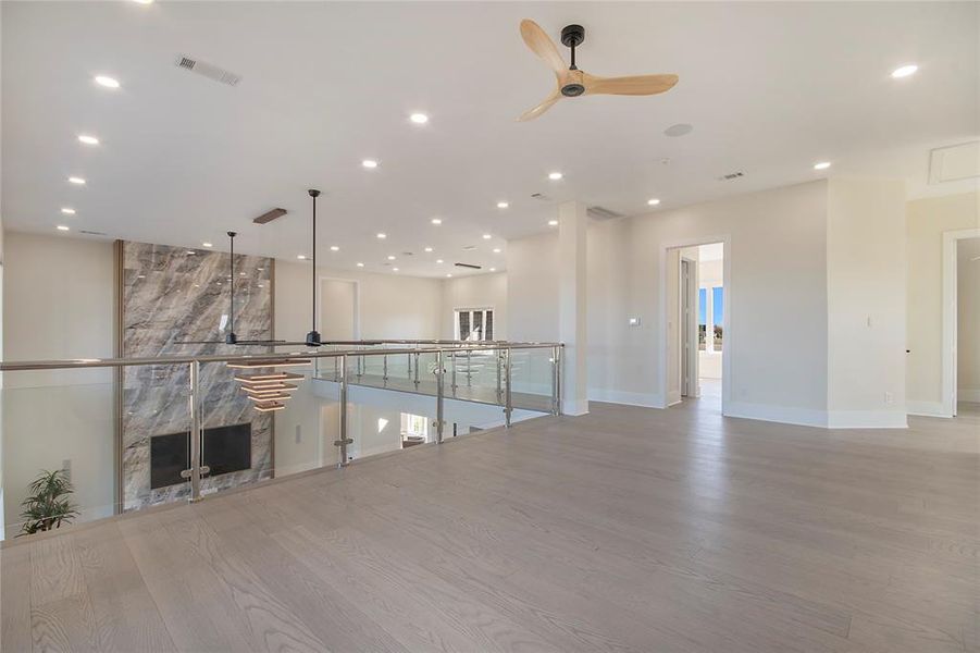 Unfurnished living room with a ceiling fan, recessed lighting, light wood finished floors, and a fireplace Unfurnished living room with a ceiling fan, recessed lighting, light wood finished floors, and a fireplace