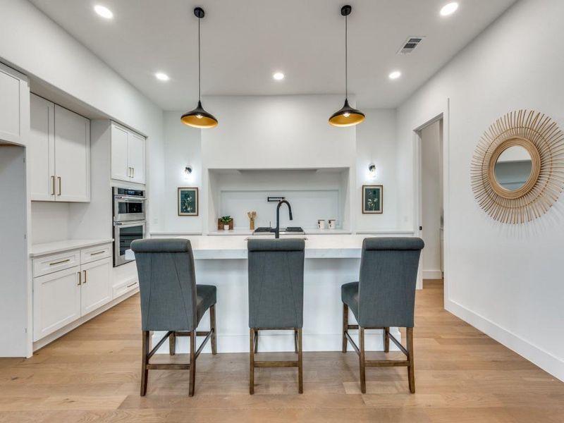 Kitchen with pendant lighting, light wood-type flooring, and white cabinetry