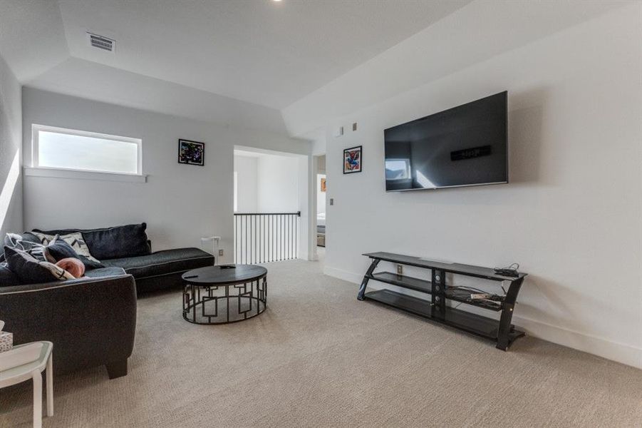 Living area with light carpet and a tray ceiling