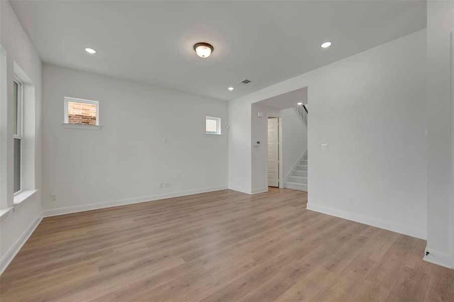 Spacious living area featuring wood-finish flooring, recessed lighting, and bright white walls