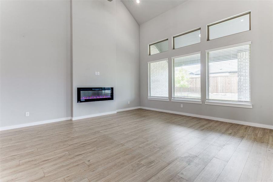 Unfurnished living room with high vaulted ceiling and light hardwood / wood-style floors