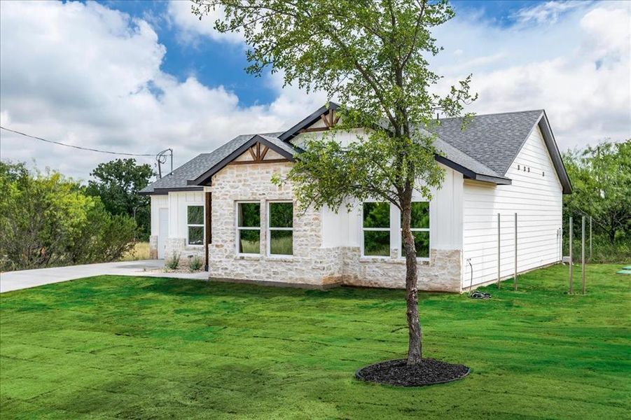 Modern farmhouse exterior featuring white board and batten siding and light-toned stone accents