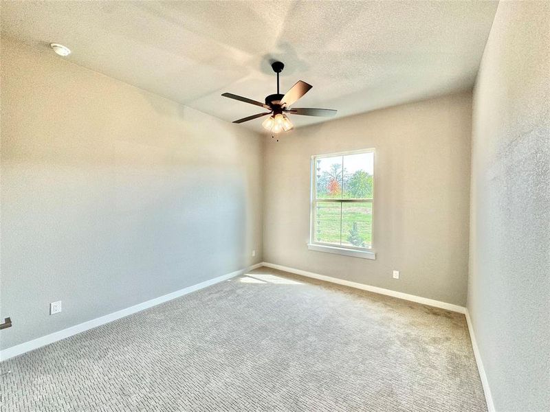 Carpeted spare room with a ceiling fan, baseboards, a textured ceiling, and a smoke detector