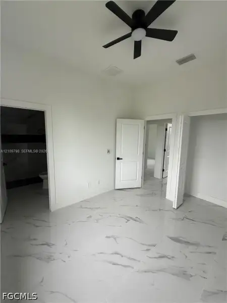 Interior space featuring polished large-format tile flooring, a matte black multi-blade ceiling fan, and solid-core paneled doors with matte black hardware