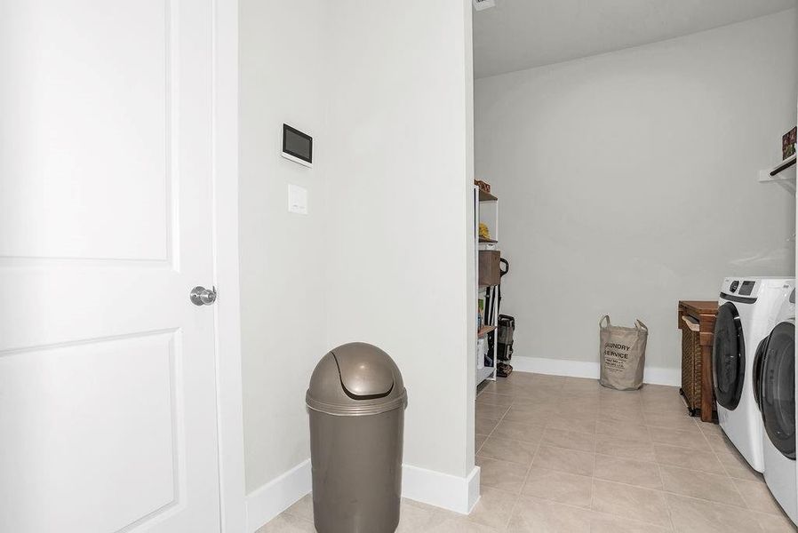 Oversized mudroom/laundry area featuring light-toned tile flooring, electric connections and extra drying space.