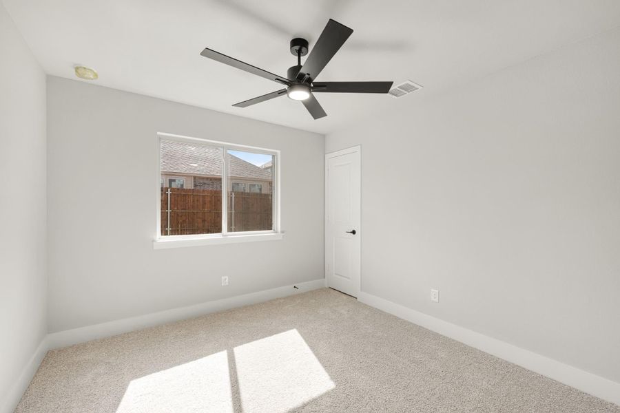 Empty bedroom with carpet flooring, black ceiling fan, and single window with natural light Empty bedroom with carpet flooring, black ceiling fan, and single window with natural light
