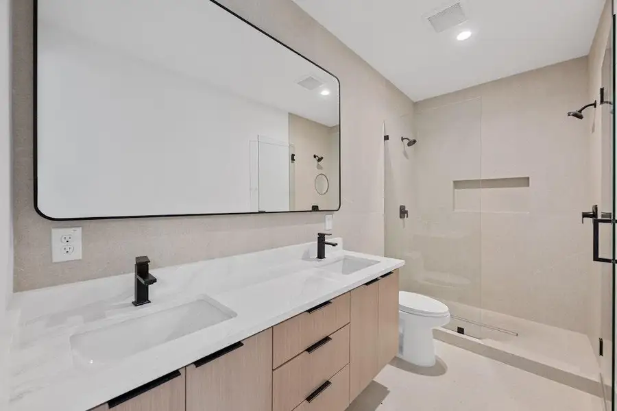 Bathroom with a shower stall, double vanity, and recessed lighting