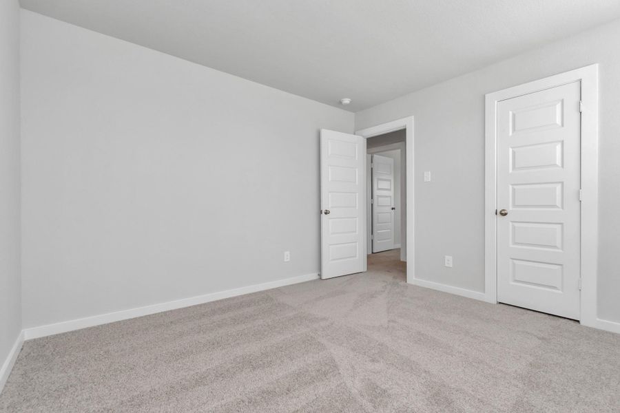 Secondary bedrooms showcase 5-panel doors adorned with modern hardware, large windows enhanced by privacy blinds, and spacious closets featuring sleek and contemporary finishes. Sample photo of completed home with similar floor plan. Actual colors and selections may vary.