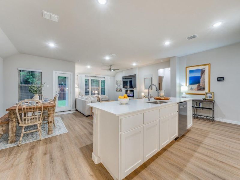 Kitchen featuring light hardwood / wood-style floors, white cabinetry, dishwasher, a center island with sink, and sink