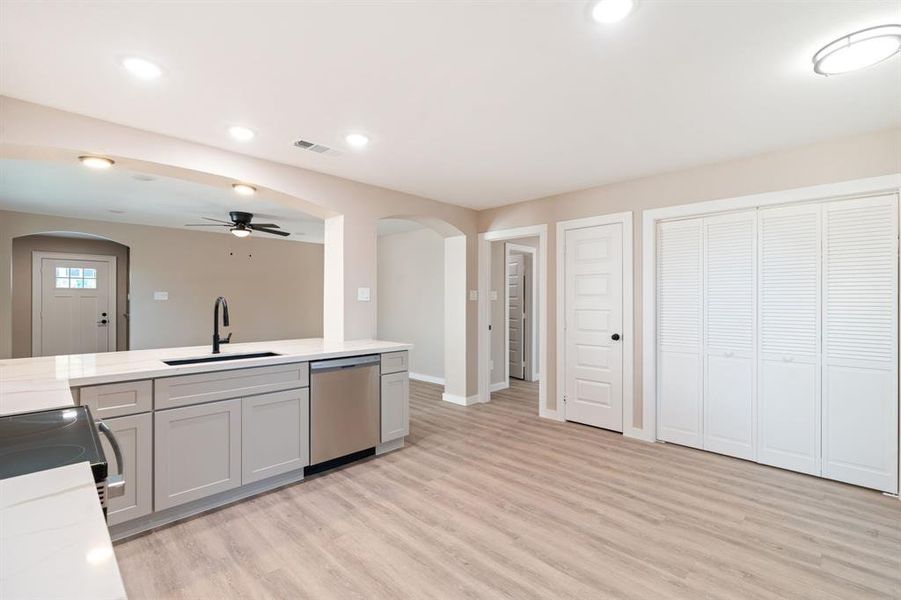 Kitchen with arched walkways, gray cabinets, light stone countertops, recessed lighting, and stainless steel appliances