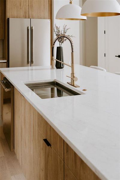 Kitchen featuring appliances with stainless steel finishes, light wood-type flooring, sink, and light stone countertops