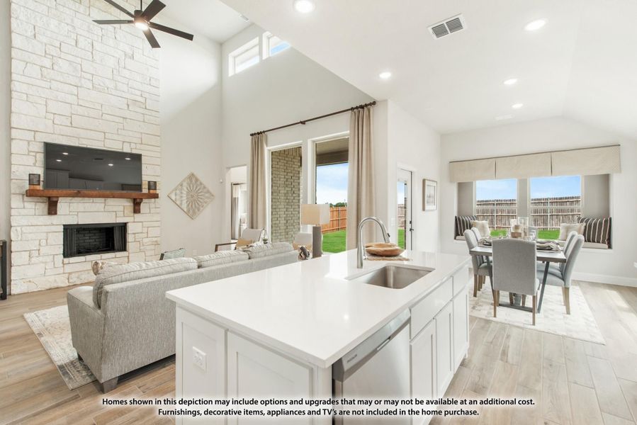Open-concept living area with kitchen island, stone fireplace, high ceilings, and dining space visible in background.
