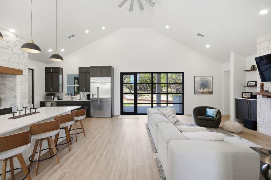 Vaulted ceilings and wide-plank wood flooring define this open-concept main living and dining space.