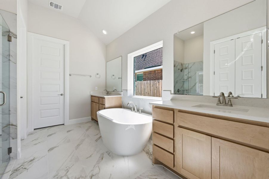 Bathroom with a marble finish shower, a freestanding bath, light marble finish floors, two vanities, and lofted ceiling Bathroom with a marble finish shower, a freestanding bath, light marble finish floors, two vanities, and lofted ceiling