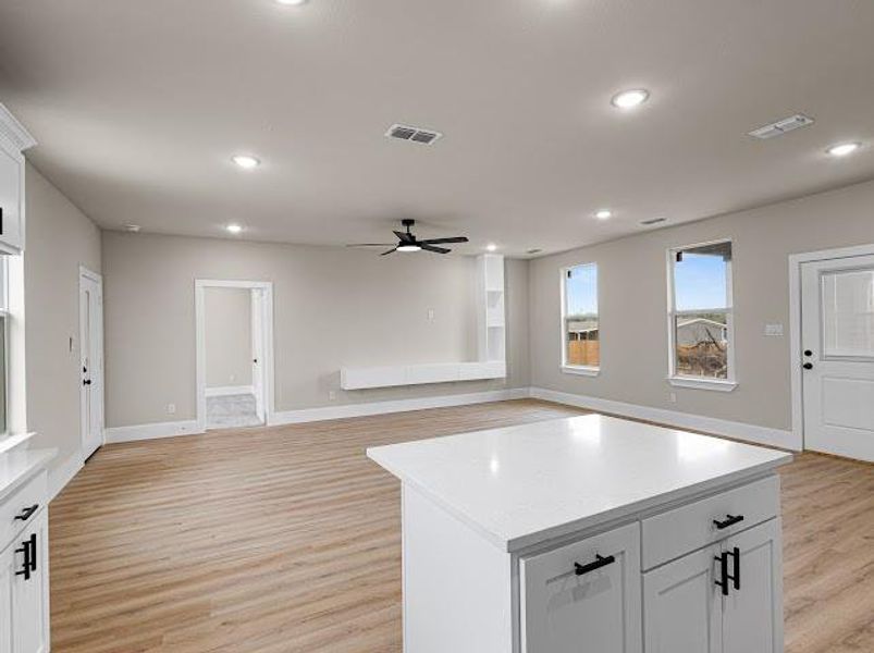 Kitchen with white cabinets, open floor plan, light wood-type flooring, recessed lighting, and a ceiling fan Kitchen with white cabinets, open floor plan, light wood-type flooring, recessed lighting, and a ceiling fan