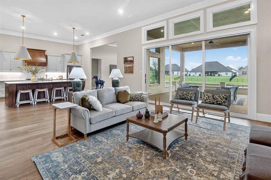 Living area with light wood-type flooring, crown molding, recessed lighting, and a residential view