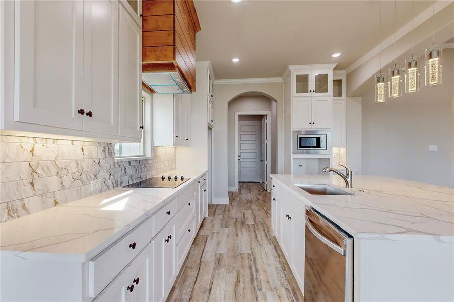 Kitchen with white cabinetry, stainless steel appliances, light stone countertops, and sink