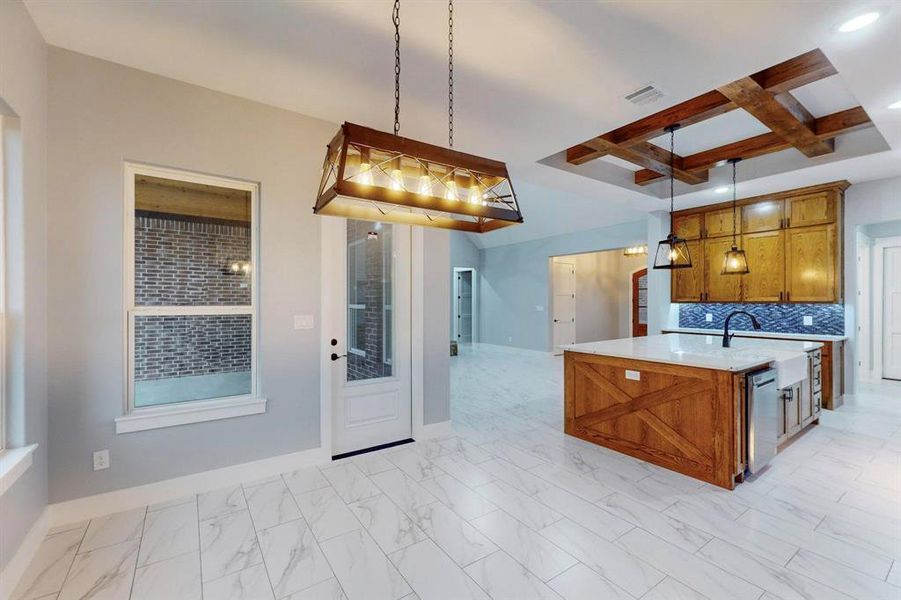 Kitchen featuring pendant lighting, a center island with sink, tasteful backsplash, and coffered ceiling