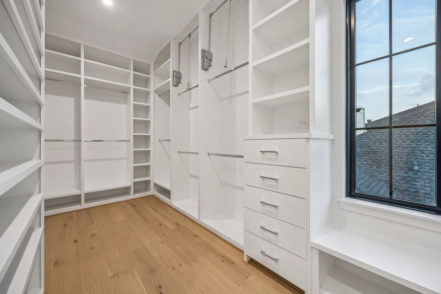Partial view of the Primary Closet with built-in dresser drawers, pulldowns, chrome rods and more.