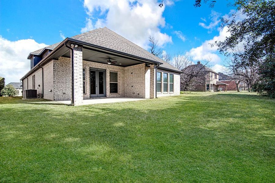 Back of house with central air condition unit, ceiling fan, french doors, and a yard