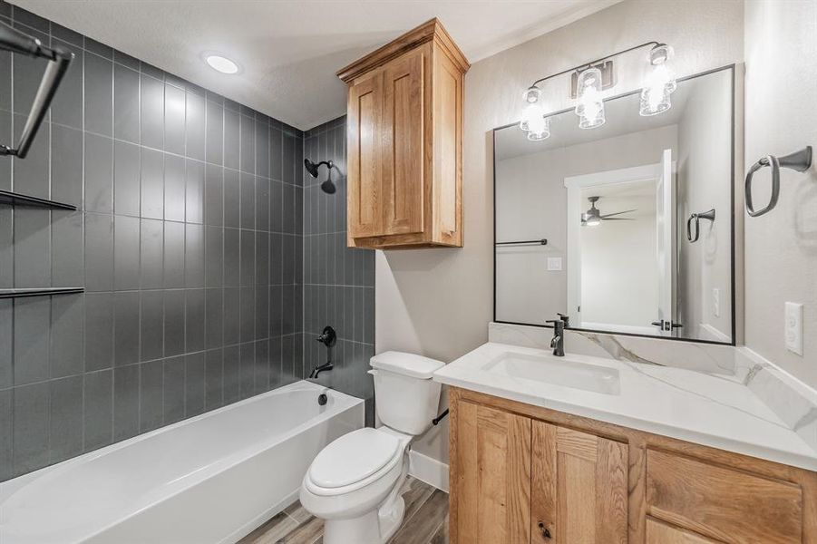 Full bathroom with vanity, bathing tub / shower combination, wood finished floors, and ceiling fan Full bathroom with vanity, bathing tub / shower combination, wood finished floors, and ceiling fan