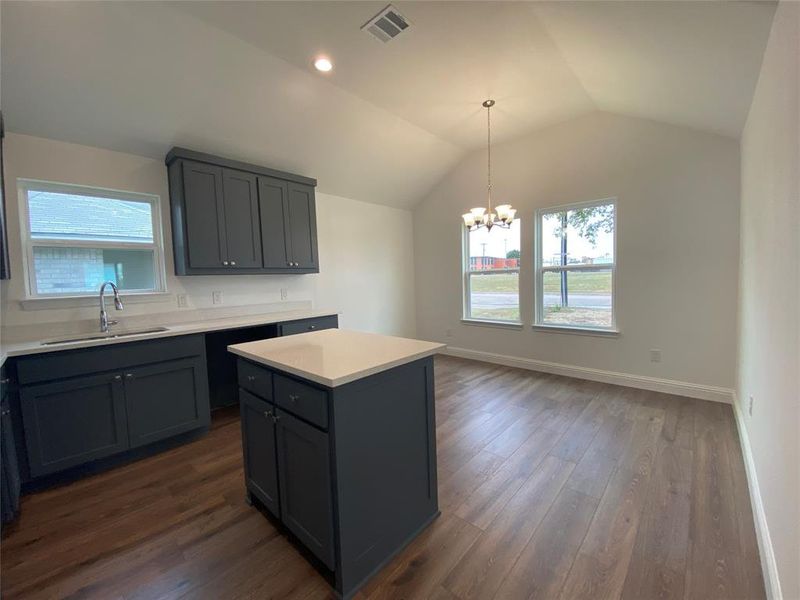 Kitchen with a chandelier, lofted ceiling, dark wood-style flooring, hanging light fixtures, and a center island Kitchen with a chandelier, lofted ceiling, dark wood-style flooring, hanging light fixtures, and a center island