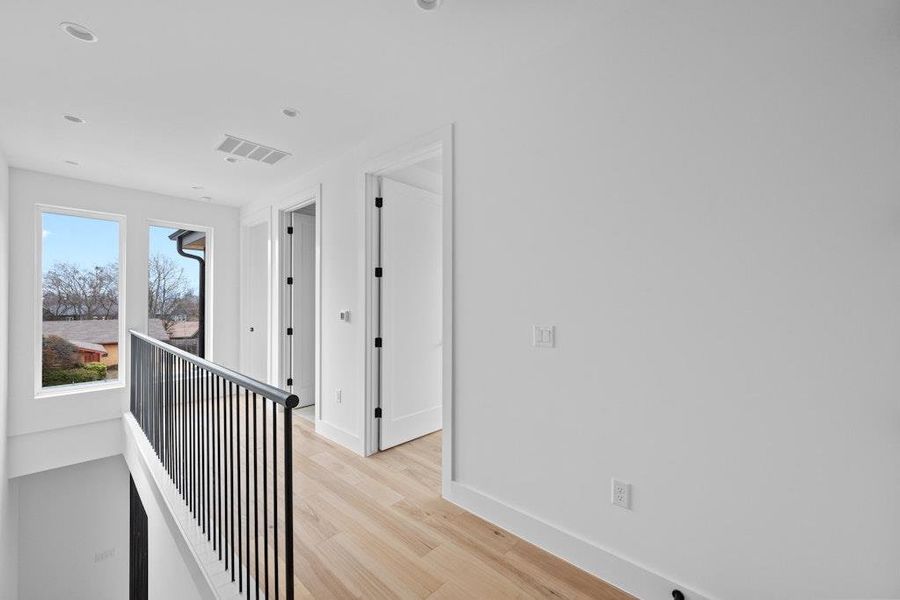 Corridor with an upstairs landing, light wood-style flooring, and recessed lighting