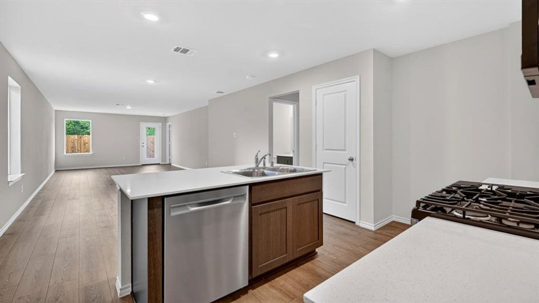 Open-concept kitchen and living area featuring wood-finish flooring, recessed lighting, and light gray walls