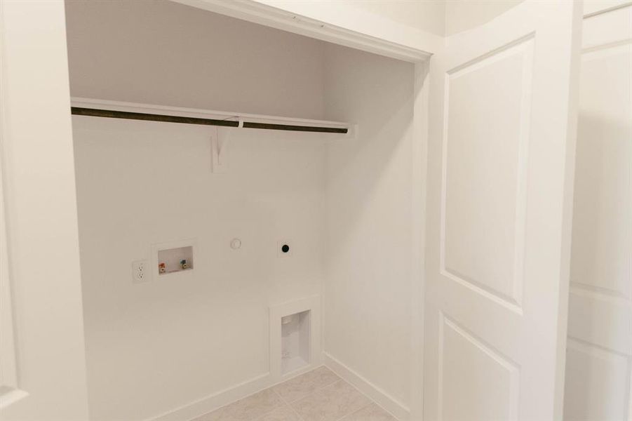 Clothes washing area with hookup for a washing machine, gas dryer hookup, hookup for an electric dryer, and light tile patterned floors