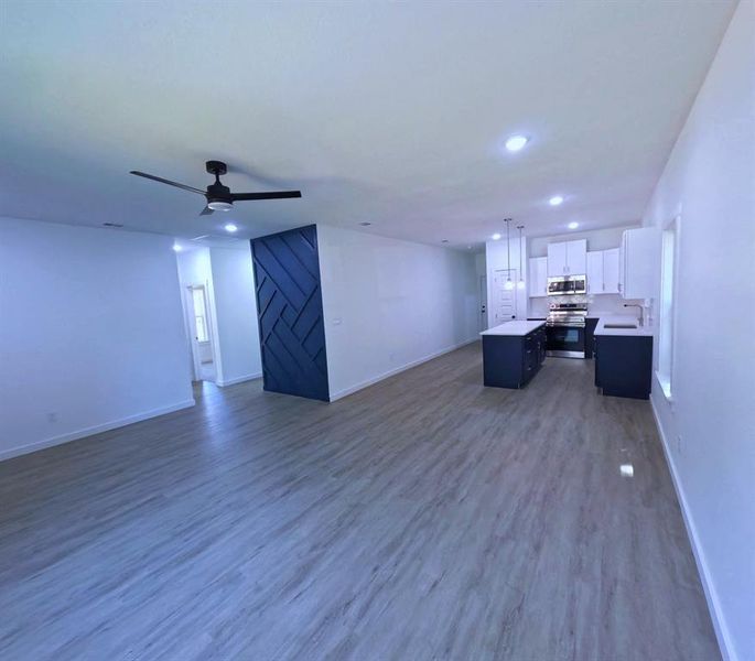 Unfurnished living room with dark wood-style flooring, ceiling fan, recessed lighting, and a barn door Unfurnished living room with dark wood-style flooring, ceiling fan, recessed lighting, and a barn door