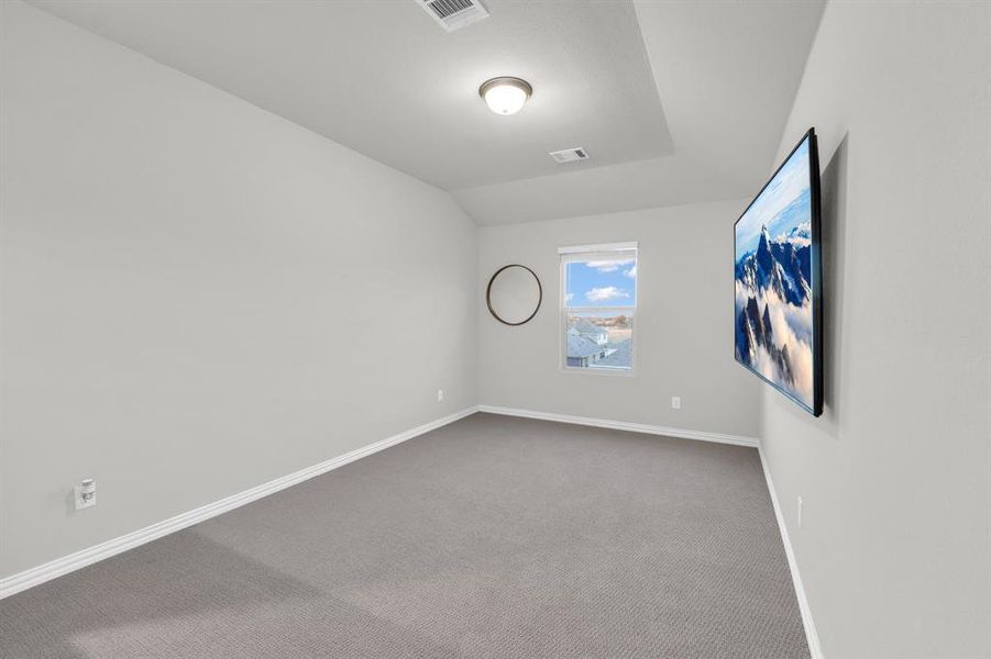 Carpeted empty room with lofted ceiling